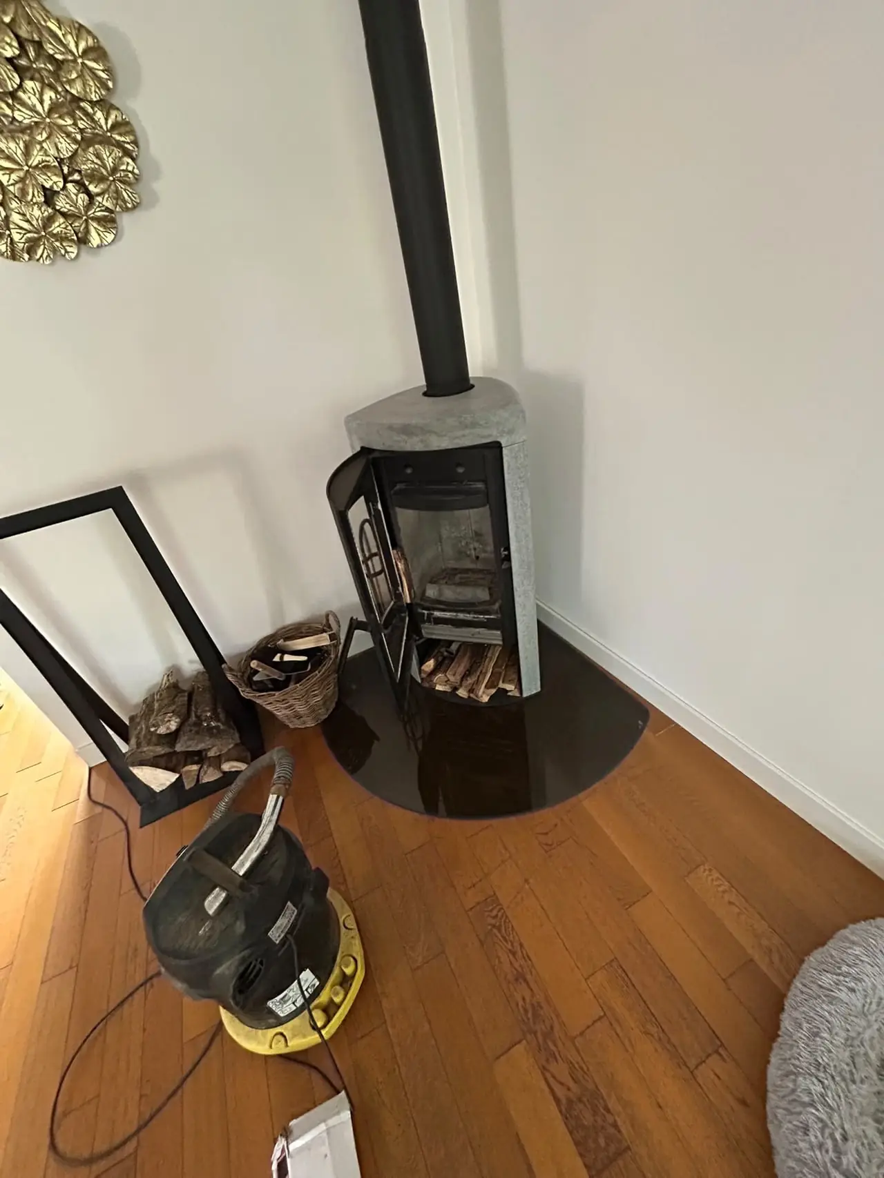 Poêle à bois habillé de pierre, porte ouverte, aspirateur à cendres de l'intervention au premier plan